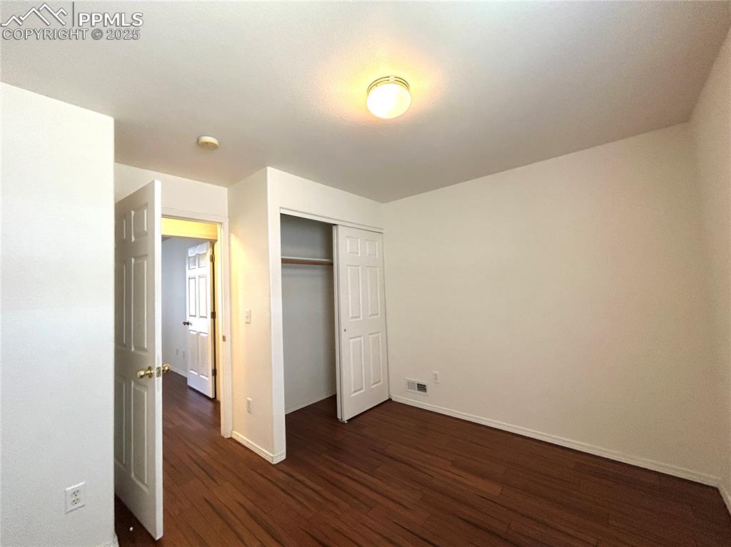 Image 25 of 43: Unfurnished bedroom featuring a closet, baseboards, visible vents, and dark