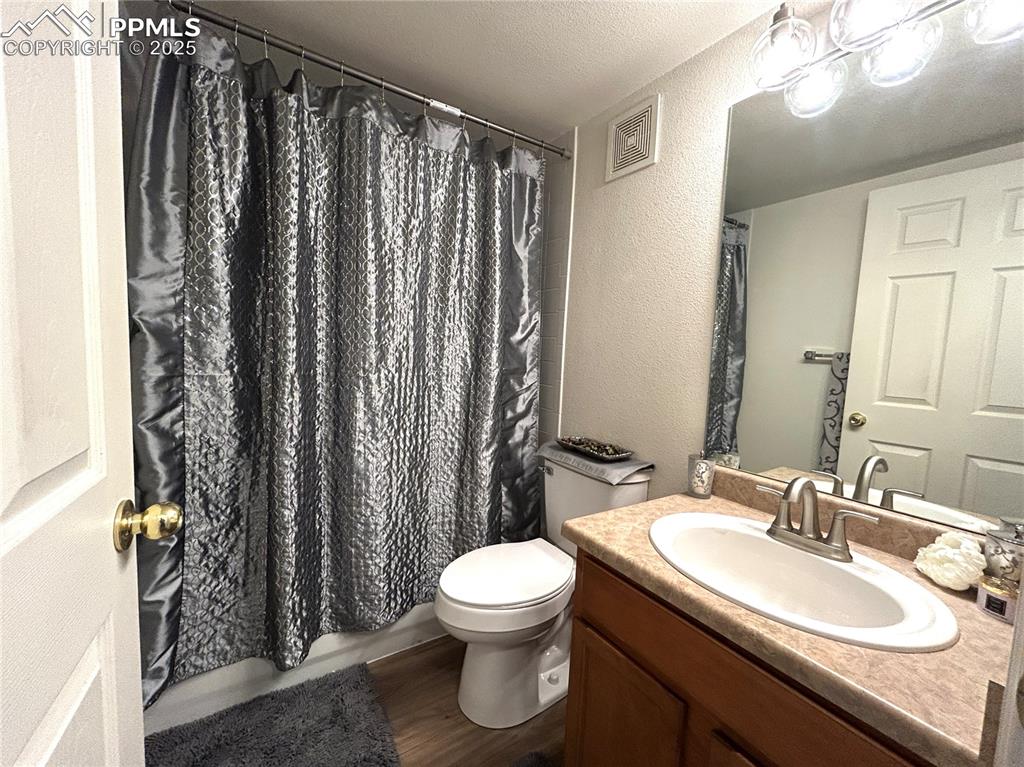 Image 26 of 43: Full bath with visible vents, vanity, a textured wall, wood finished floors