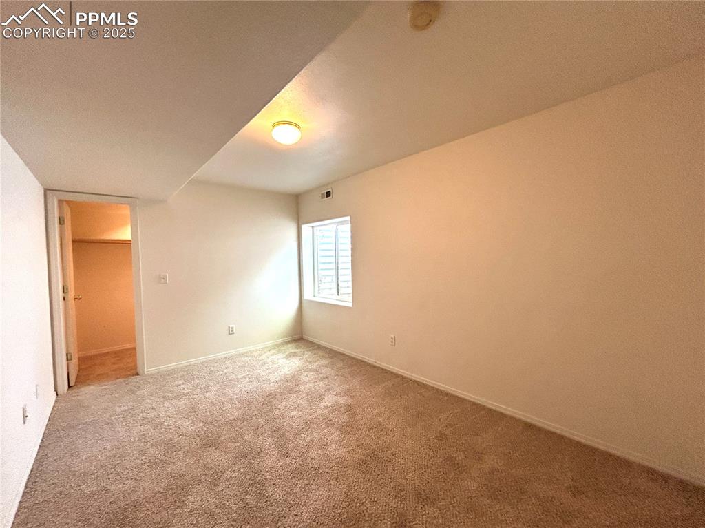 Image 37 of 43: Unfurnished bedroom with carpet flooring, baseboards, visible vents, and a 