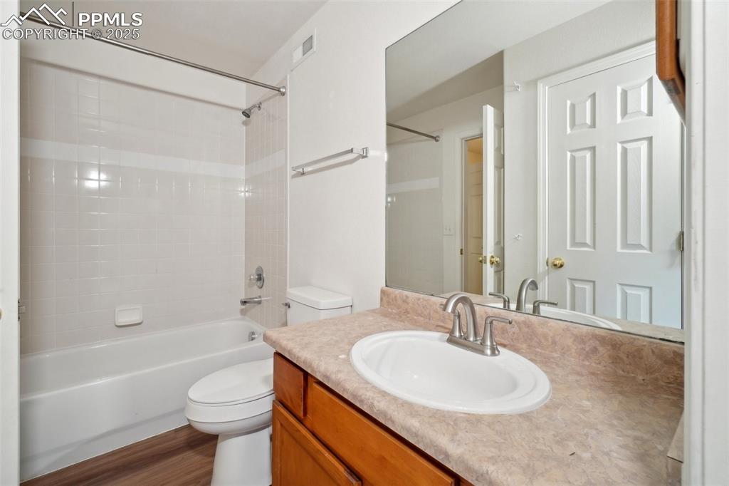 Image 40 of 43: Bathroom featuring washtub / shower combination, vanity, toilet, wood finis