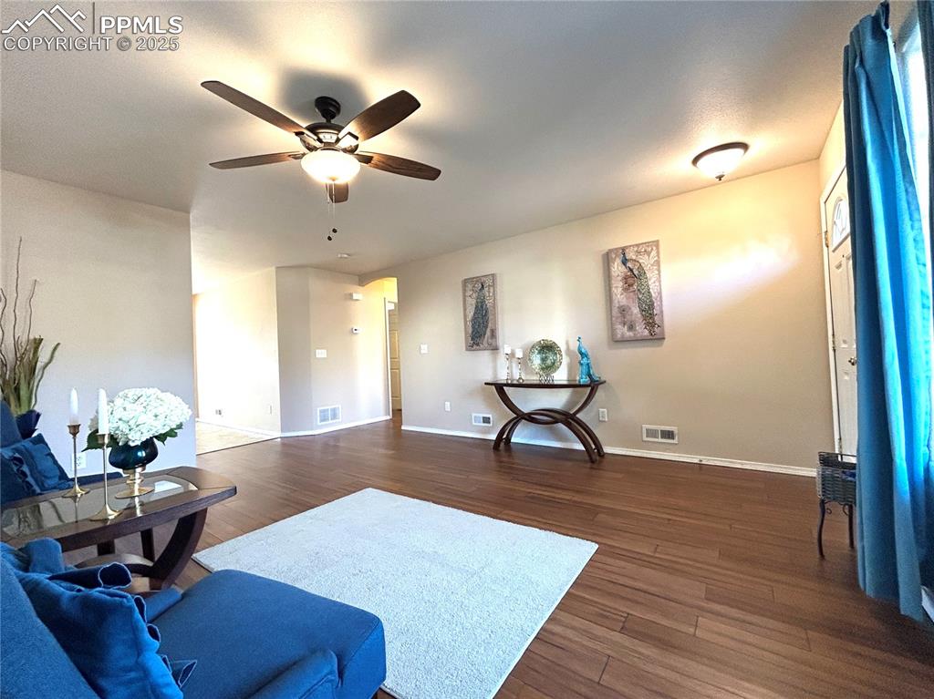 Image 6 of 43: Living room featuring a ceiling fan, dark wood finished floors, and visible