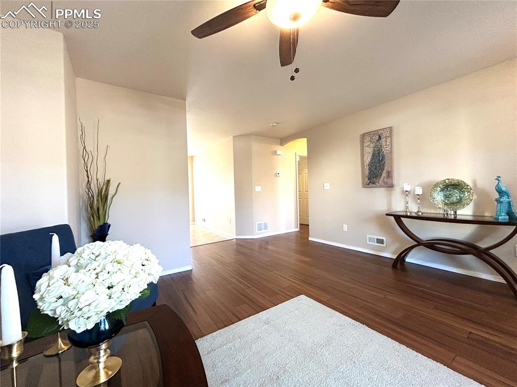 Image 7 of 43: Living room featuring a ceiling fan, baseboards, visible vents, and wood fi