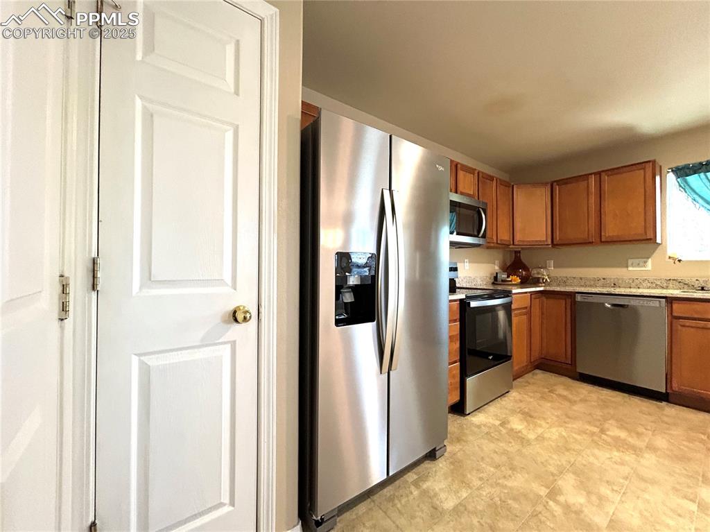 Image 9 of 43: Kitchen with appliances with stainless steel finishes and brown cabinets