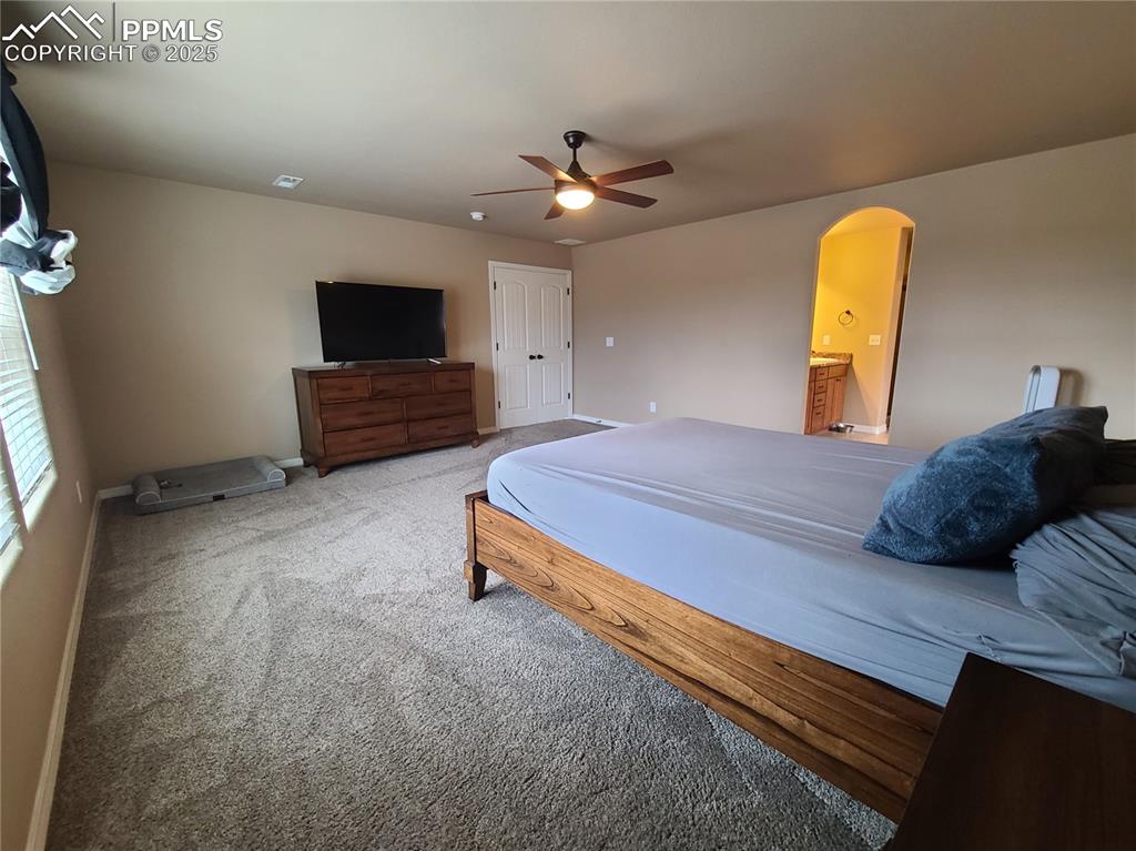 Image 16 of 29: Carpeted bedroom featuring arched walkways, ceiling fan, and ensuite bathro