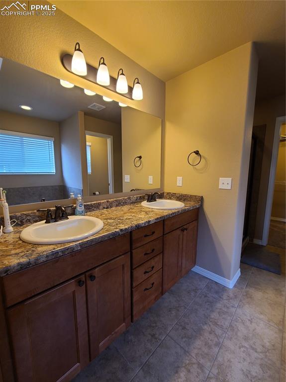 Image 18 of 29: Bathroom featuring double vanity, dark tile patterned floors, and a closet