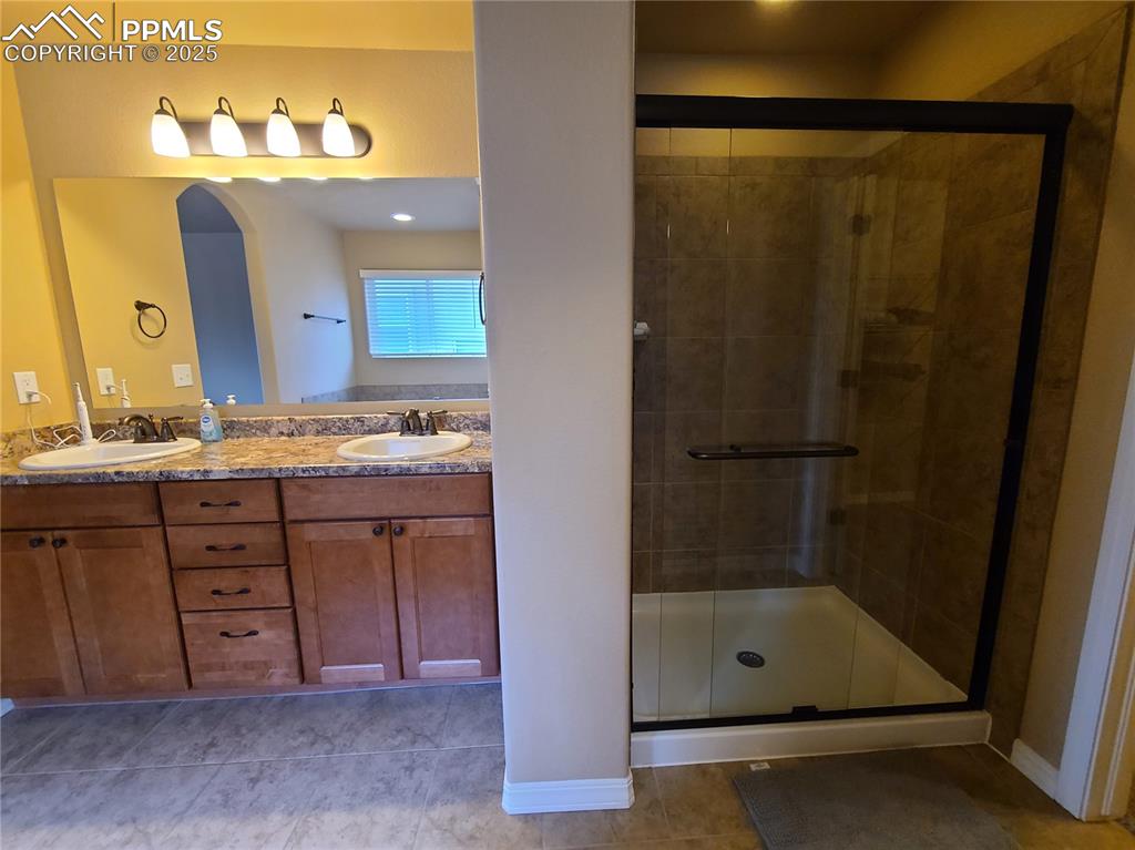 Image 19 of 29: Full bathroom with a stall shower, light tile patterned floors, and double 