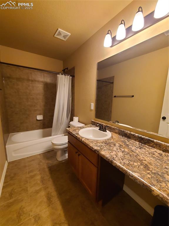 Image 23 of 29: Bathroom with shower / bath combo with shower curtain, vanity, and dark til
