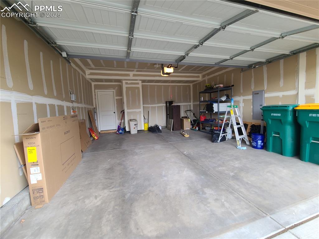 Image 3 of 29: Garage featuring electric panel and a garage door opener