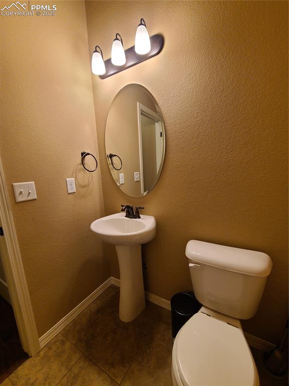 Image 7 of 29: Half bath on main level featuring a textured wall and tile patterned floori