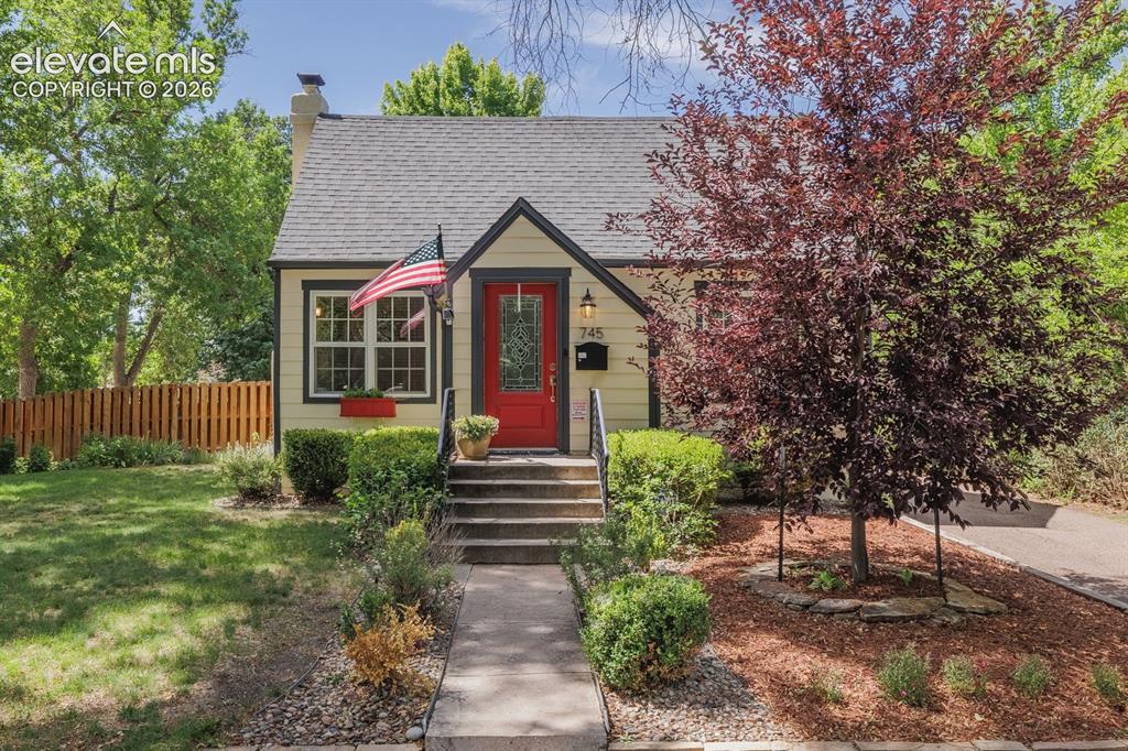 Caption: Yellow siding exterior with dark trim accents and a red entry door