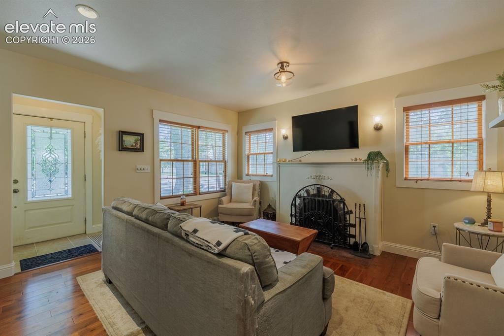 Image 10 of 49: Living area featuring a white mantel fireplace with an ornate iron screen,