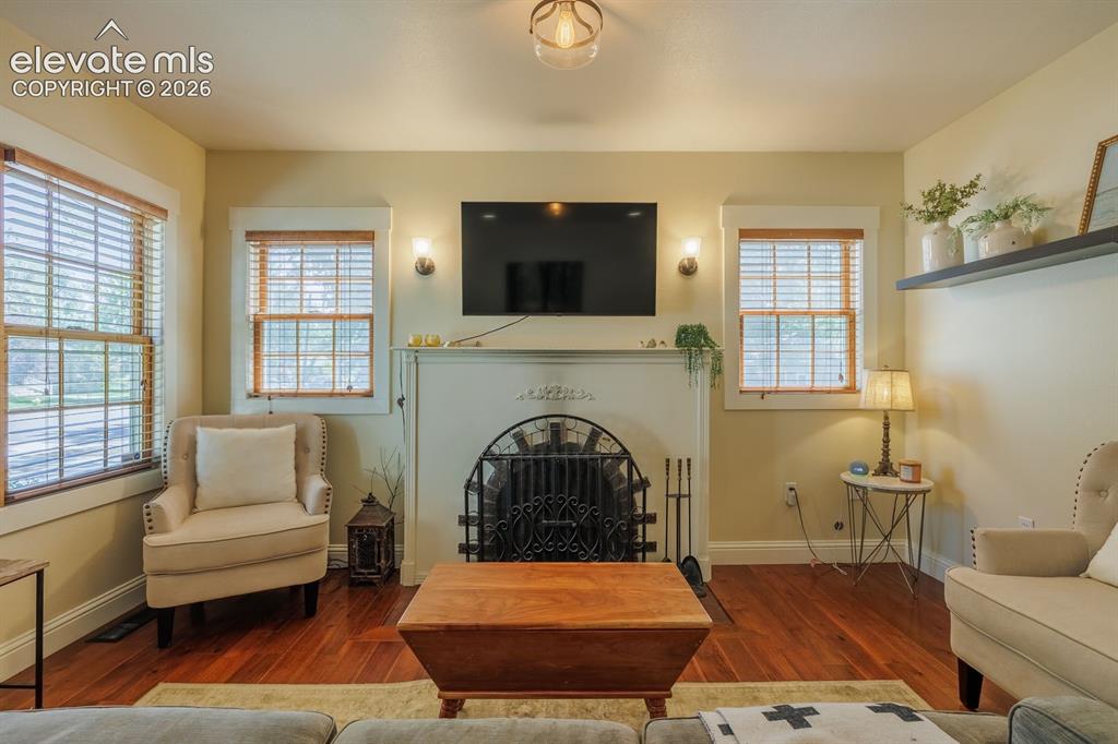 Image 11 of 49: Living area featuring a fireplace with an ornate screen, hardwood flooring,