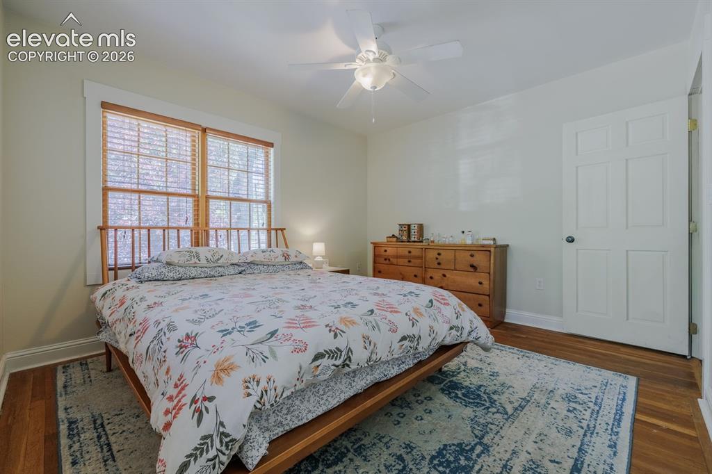 Image 13 of 49: Bedroom featuring hardwood flooring, a multi-pane window with wood blinds,