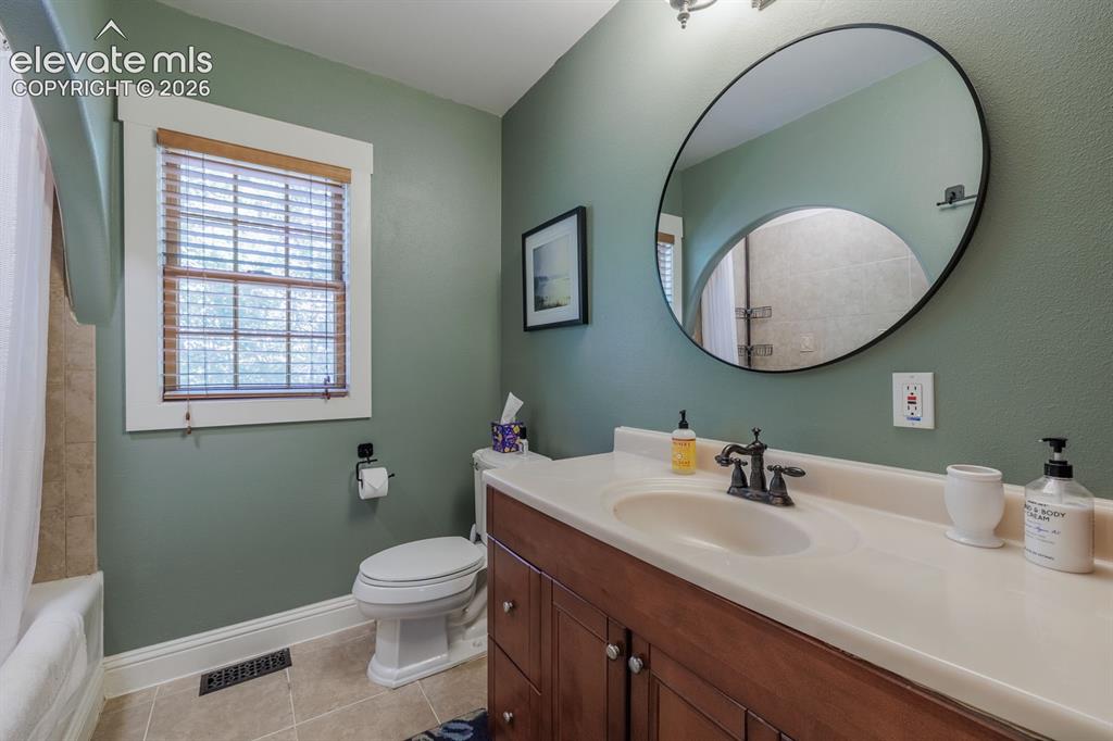 Image 15 of 49: Bathroom featuring a vanity with a light-toned countertop, wood-finish cabi