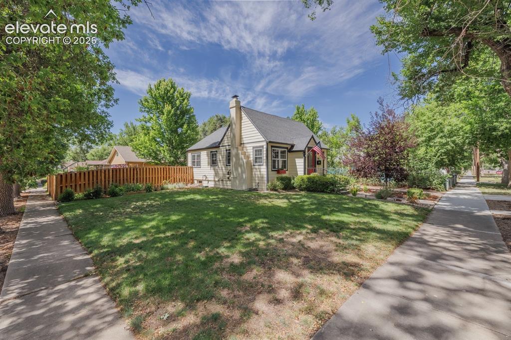 Image 2 of 49: Cream-colored exterior featuring a dark shingle roof, chimney, and multiple