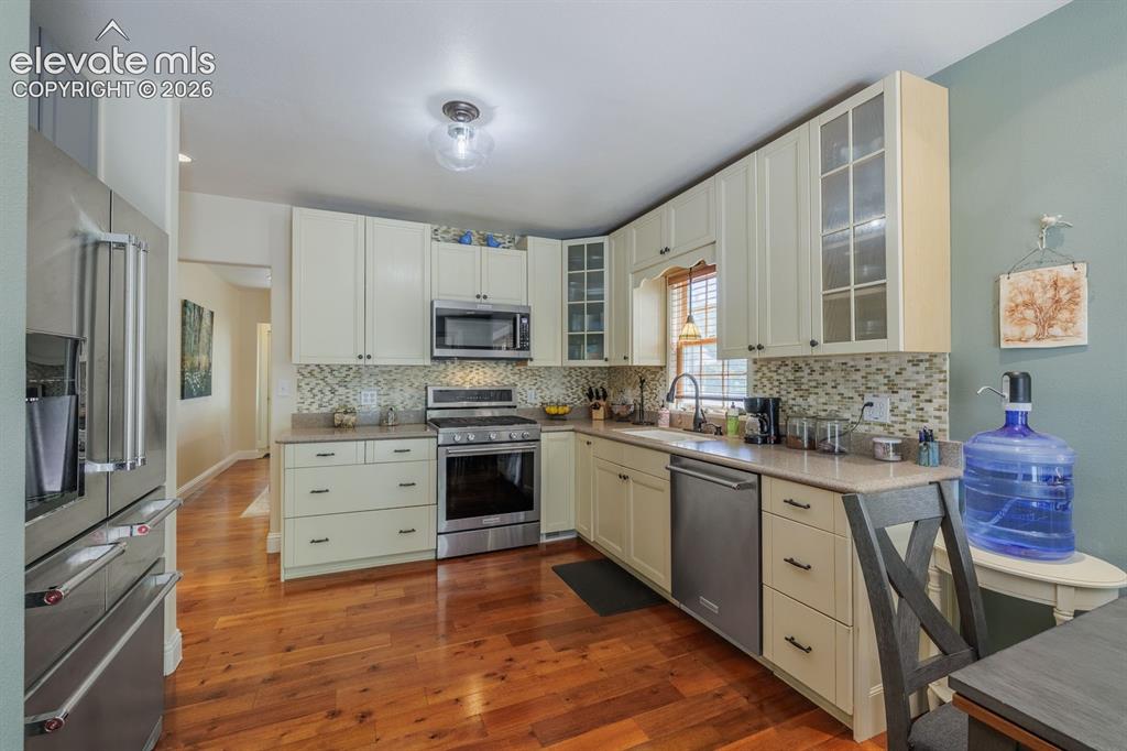 Image 21 of 49: Bright kitchen featuring warm wood-finish flooring and cream-colored cabine