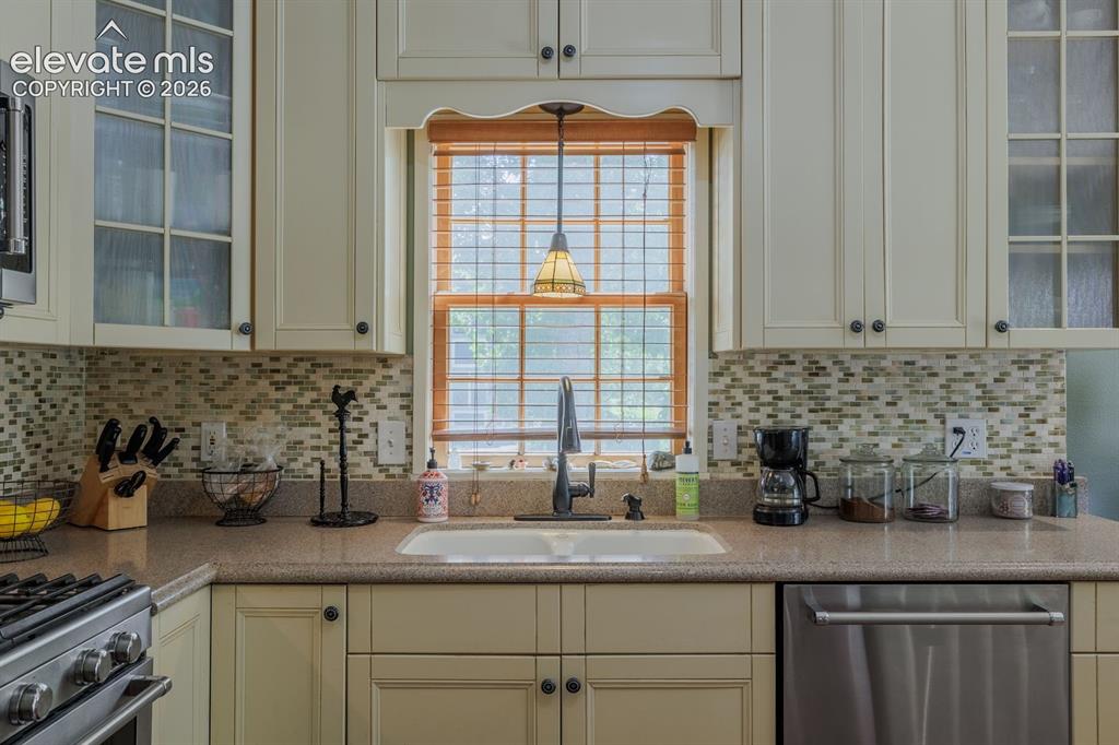 Image 24 of 49: Kitchen featuring custom cabinetry, mosaic tile backsplash, built-in stainl