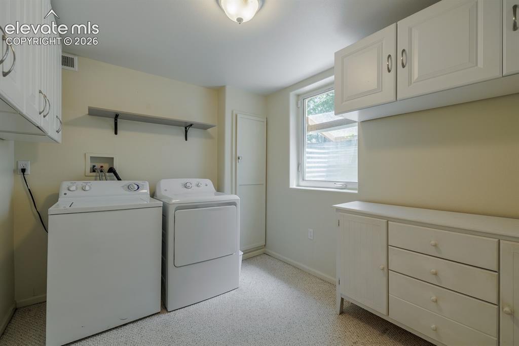 Image 32 of 49: Dedicated laundry area with carpeted flooring, a window, built-in cabinetry
