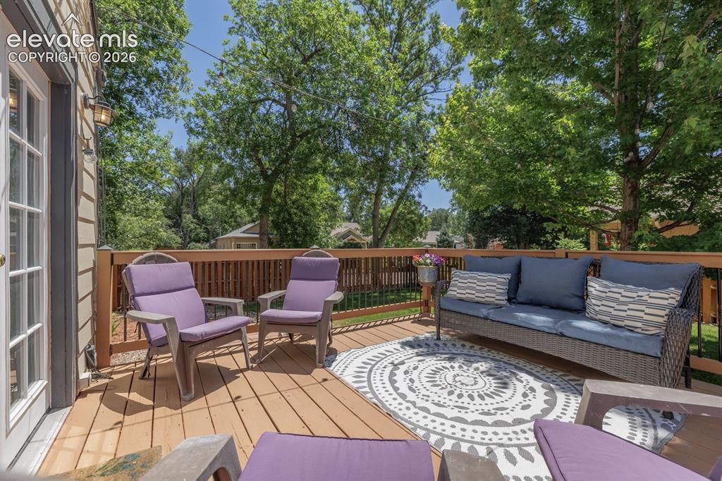 Image 36 of 49: Wood-finish deck with a perimeter railing and a cream-colored exterior wall