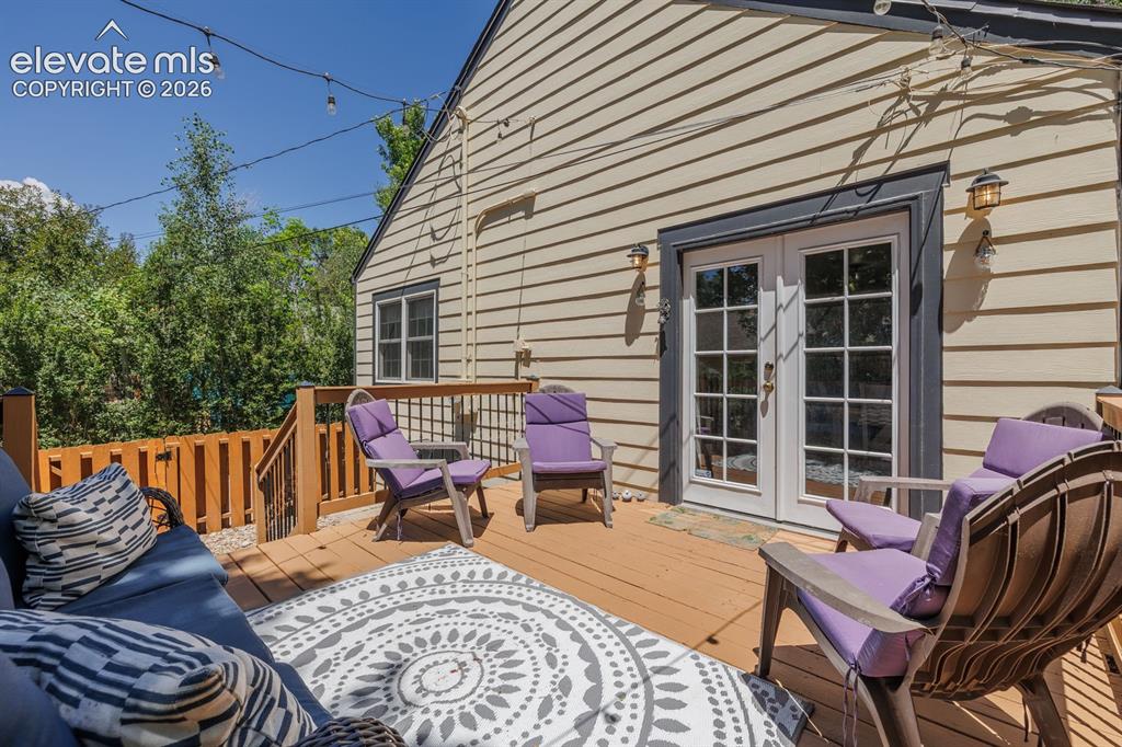 Image 37 of 49: Spacious outdoor deck with wood-finish flooring, featuring a full-glass dou