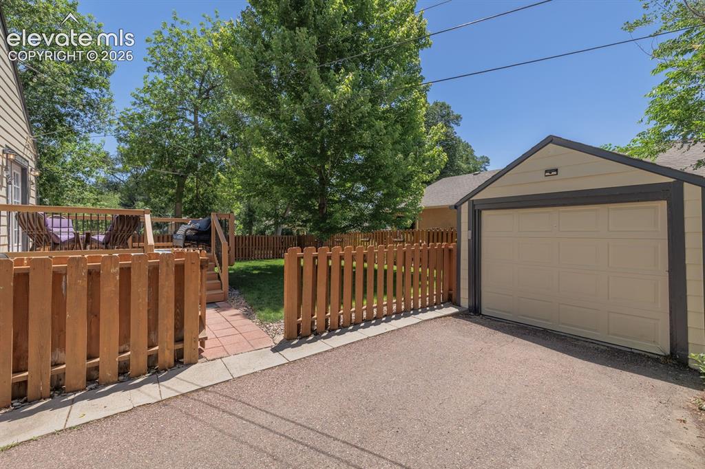Image 38 of 49: Detached garage with a paneled door and light-toned siding