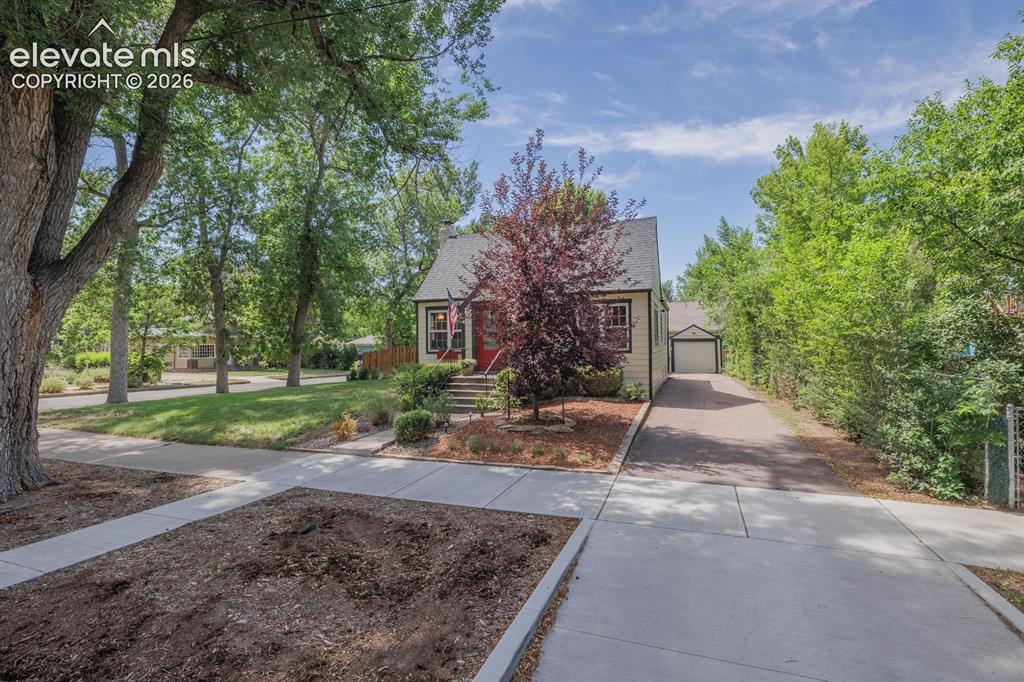 Image 4 of 49: Cream-colored exterior with a red front door, featuring a pitched roof and