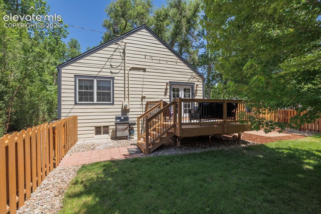 Image 40 of 49: Exterior siding with a rear wooden deck featuring black balusters, double F