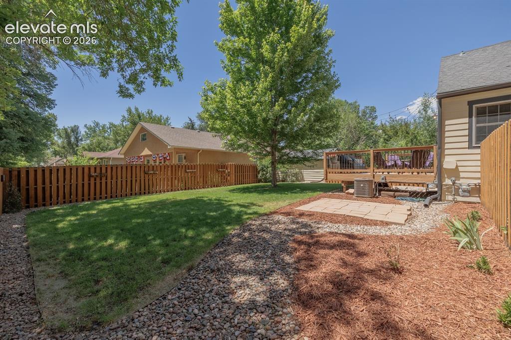 Image 42 of 49: Expansive backyard featuring a manicured lawn, a full wooden privacy fence,