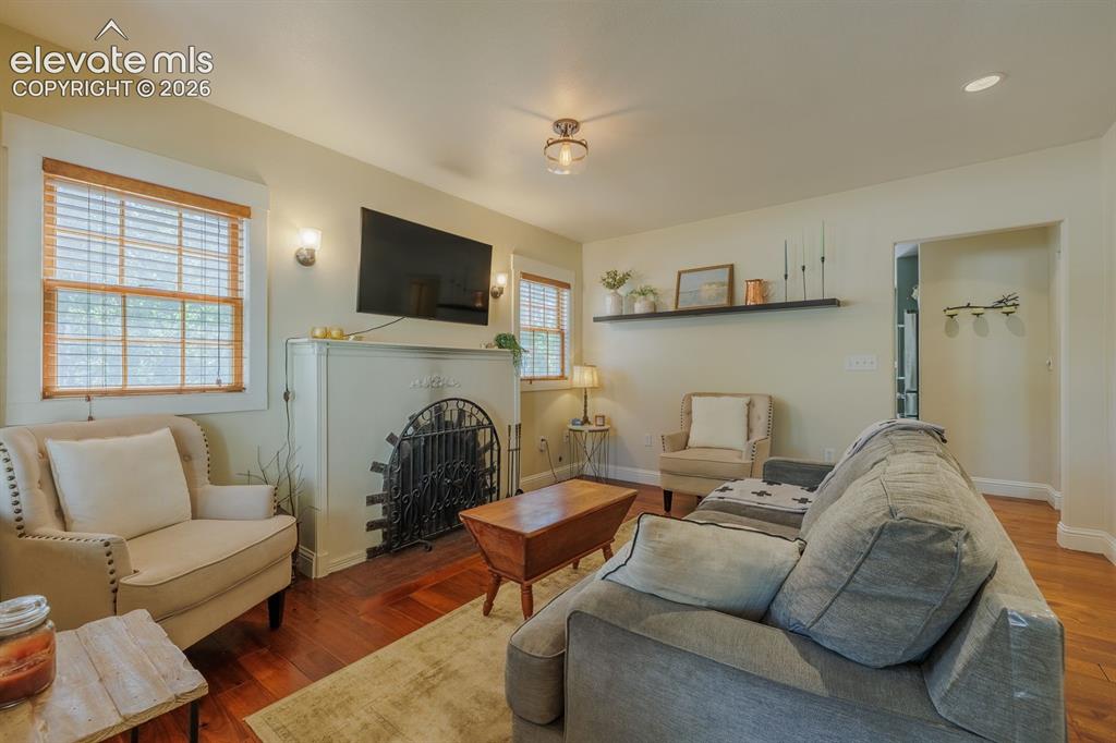 Image 7 of 49: Living area featuring wood-finish flooring, a decorative fireplace with an