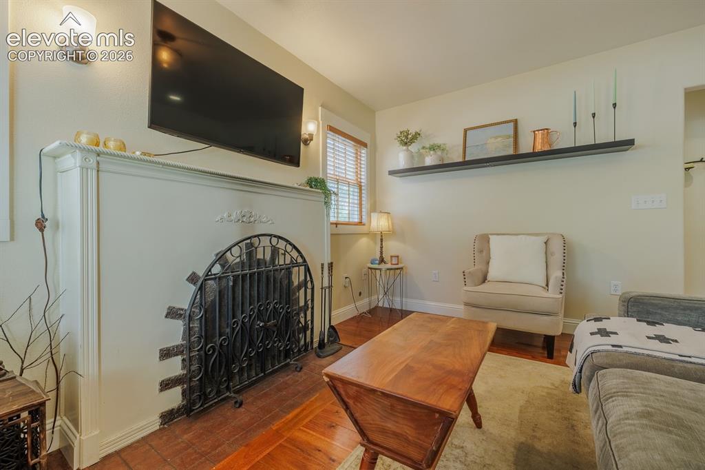 Image 8 of 49: Decorative fireplace with an ornate iron screen, sconce lighting, wood-fini