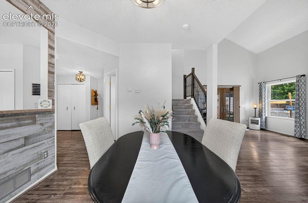 Image 15 of 30: Vaulted ceiling, wood-finish flooring, staircase with wrought iron baluster