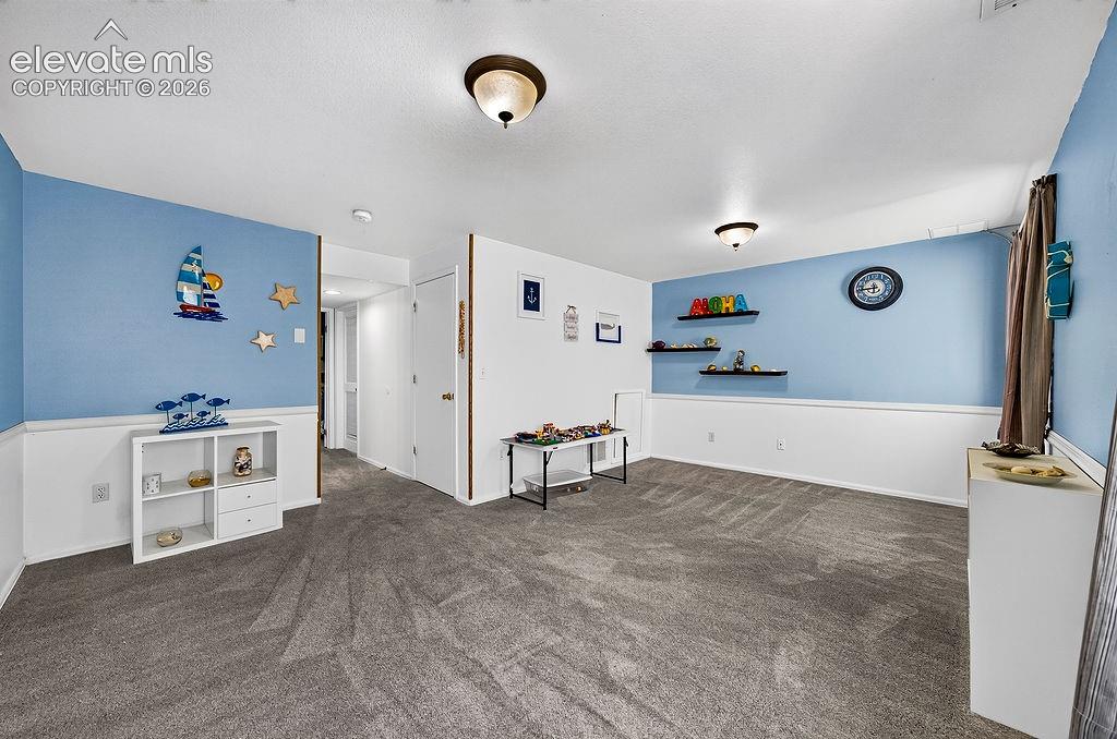 Image 25 of 30: Recessed ceiling lighting, durable carpeting, wall shelving, and white wain