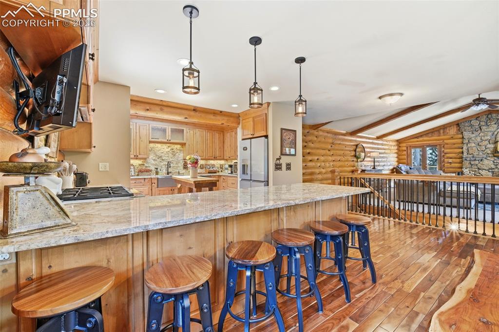 Image 10 of 50: Kitchen featuring a large breakfast bar with granite countertop, wood-finis
