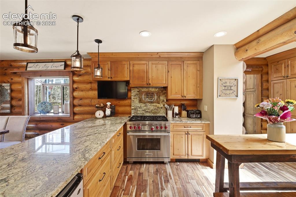 Image 10 of 49: Gourmet kitchen featuring a substantial granite island, custom wood cabinet