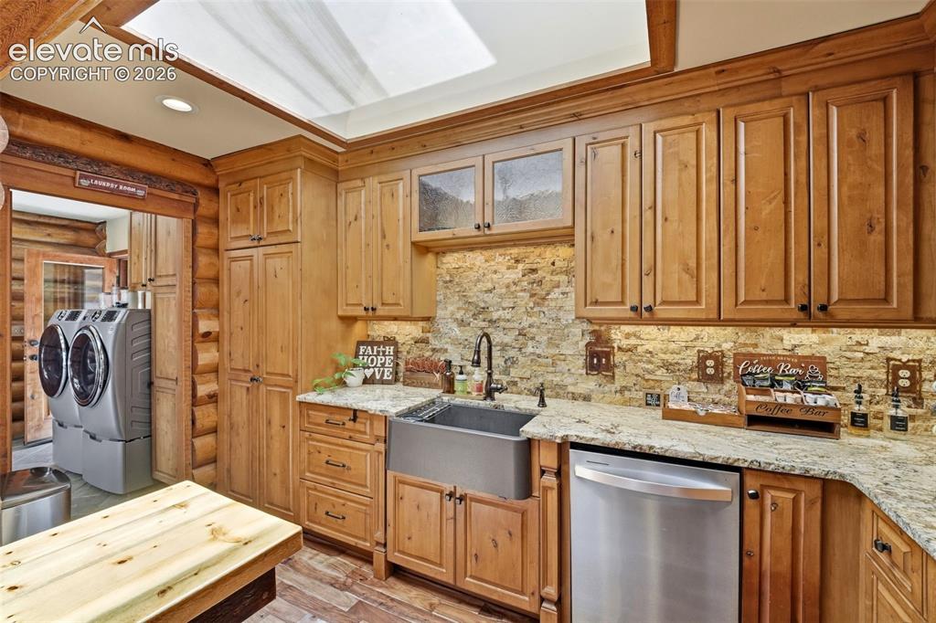 Image 11 of 49: Rustic-style kitchen featuring wood cabinetry, stone backsplash, granite co