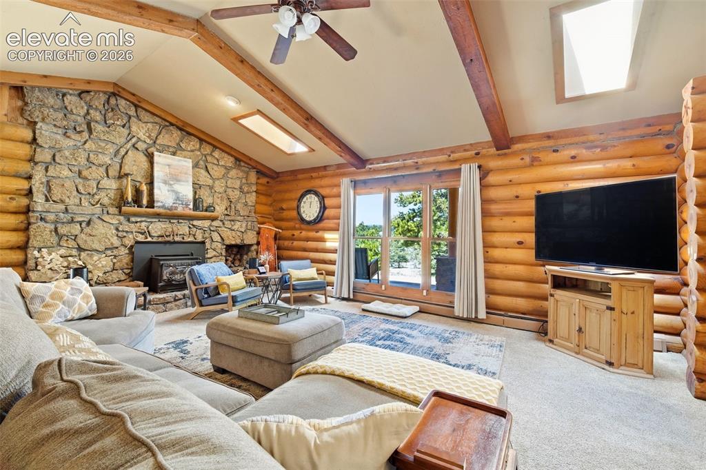 Image 15 of 49: Spacious living area featuring a vaulted ceiling with exposed wood beams, a