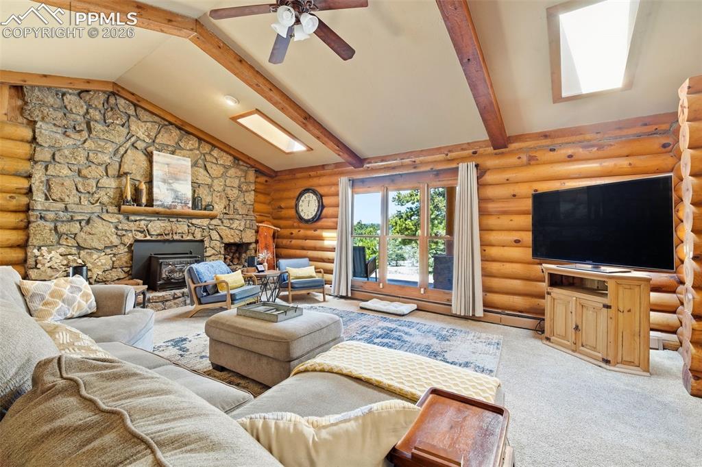 Image 16 of 50: Spacious living area featuring a vaulted ceiling with exposed wood beams, a