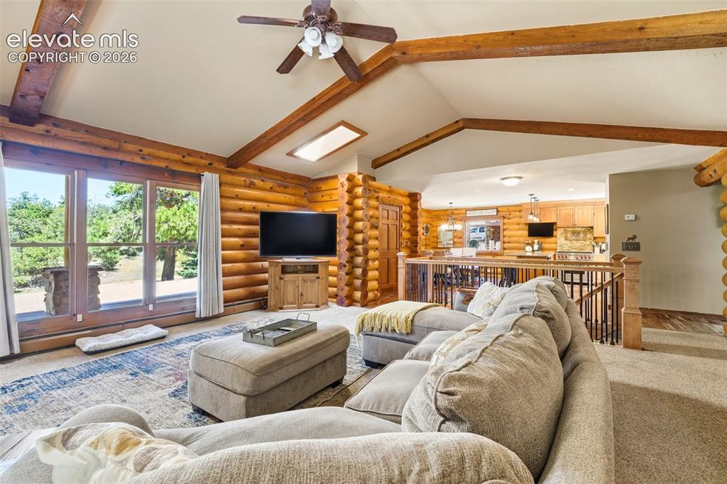 Image 16 of 49: Vaulted ceiling with exposed wood beams, log wall construction, skylight, c