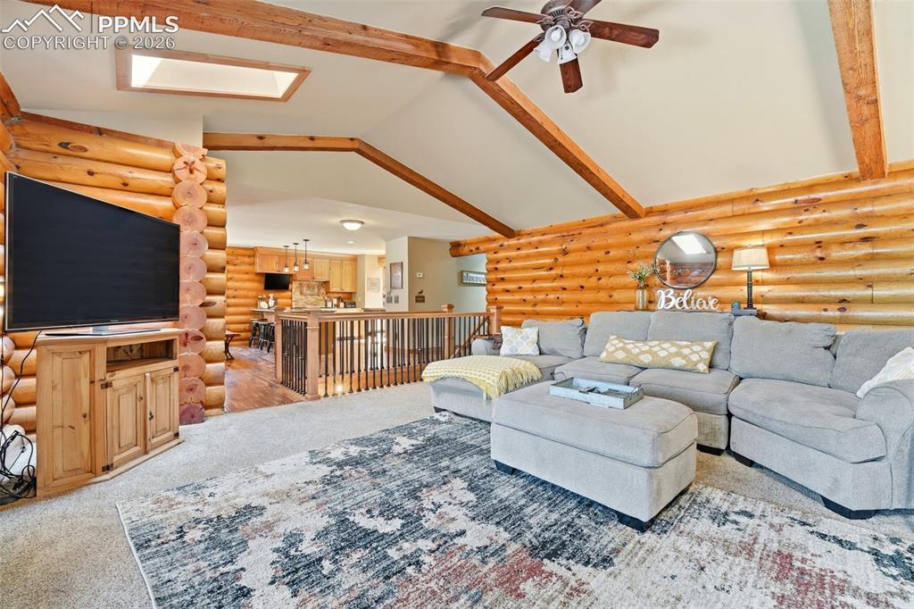 Image 19 of 50: Vaulted ceilings with exposed wood beams, skylight, and log wall constructi