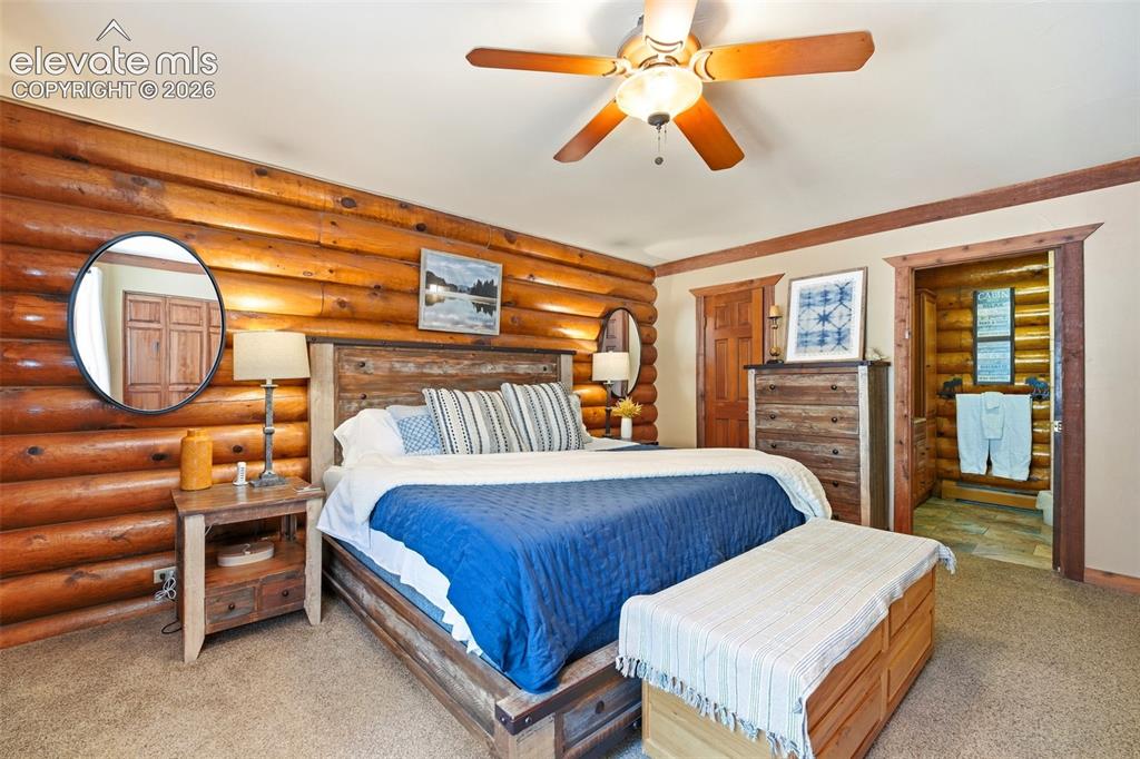 Image 19 of 49: Bedroom featuring log wall paneling, a wood-finish bed frame, wood-finish c