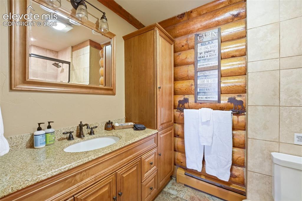 Image 20 of 49: Bathroom featuring a wood-finish vanity with an integrated sink and granite