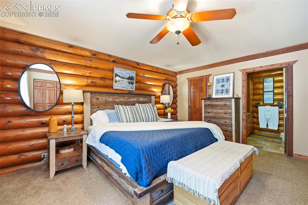 Image 21 of 50: Bedroom featuring log wall paneling, a wood-finish bed frame, wood-finish c