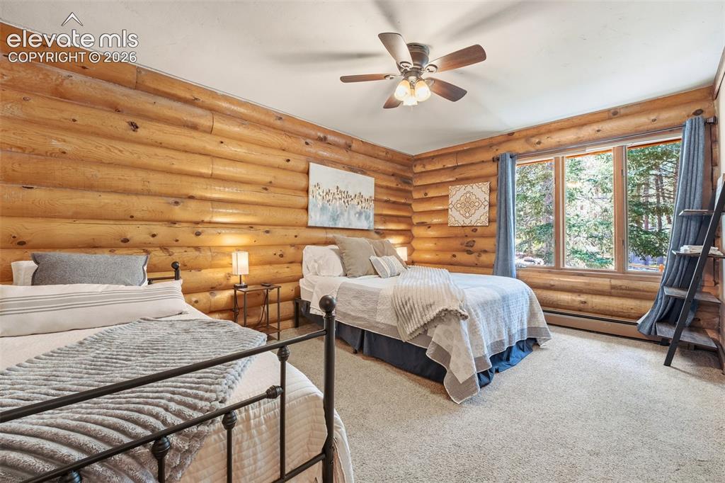 Image 22 of 49: Bedroom featuring natural log walls, neutral carpeting, and a multi-panel w