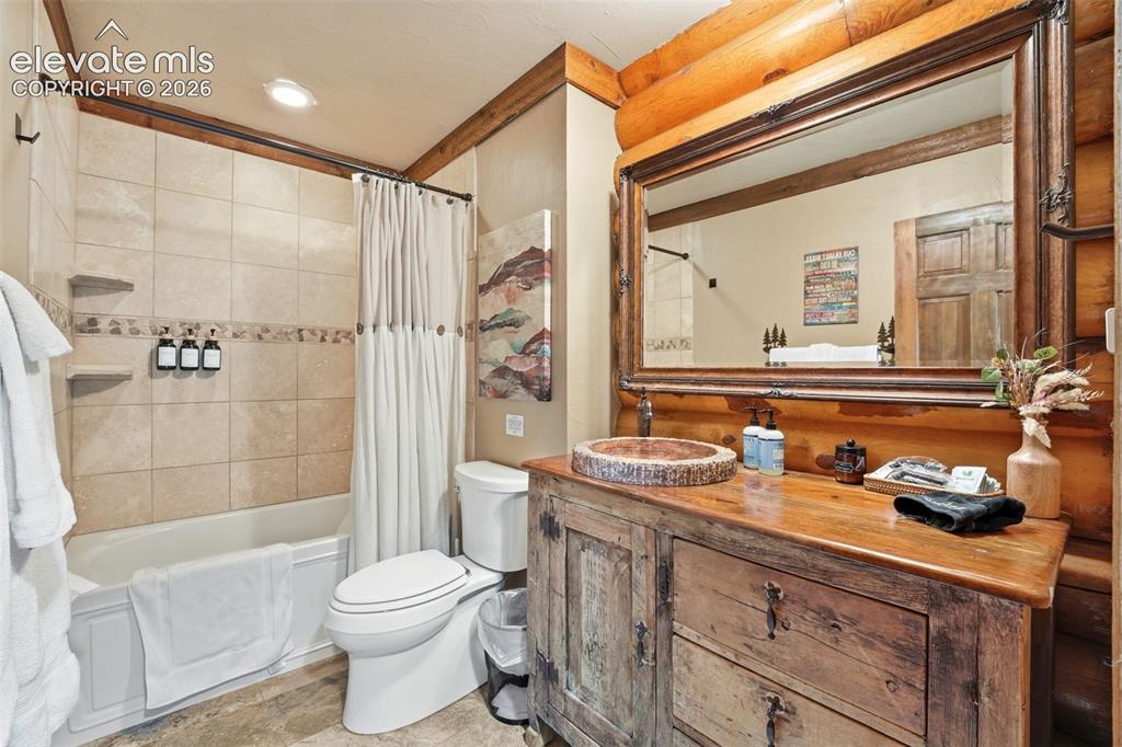Image 23 of 49: Wood-finish vanity with a vessel sink, complemented by a large framed mirro
