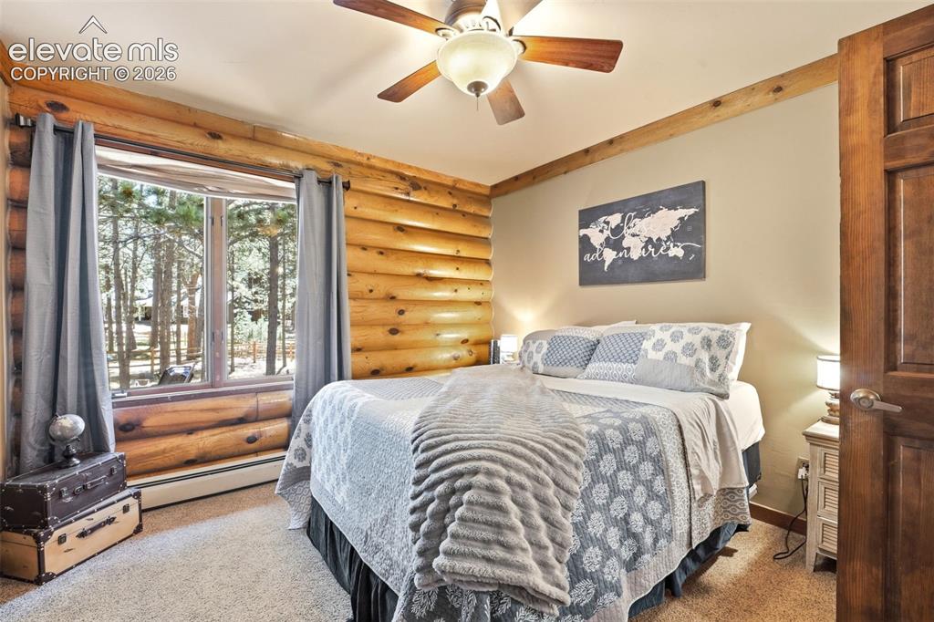 Image 24 of 49: Bedroom featuring log walls, a ceiling fan with light fixture, a window wit