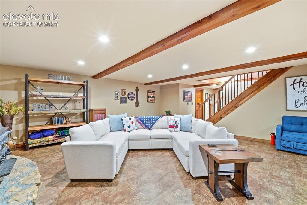 Image 25 of 49: Expansive living area with wood-finish flooring, exposed ceiling beams, rec