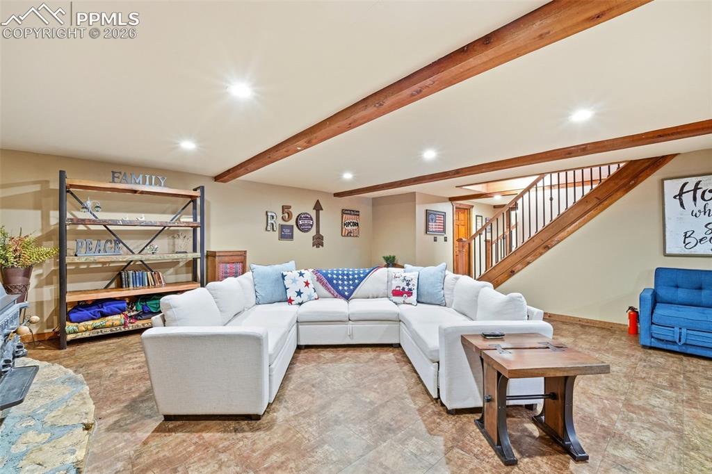 Image 27 of 50: Expansive living area with wood-finish flooring, exposed ceiling beams, rec