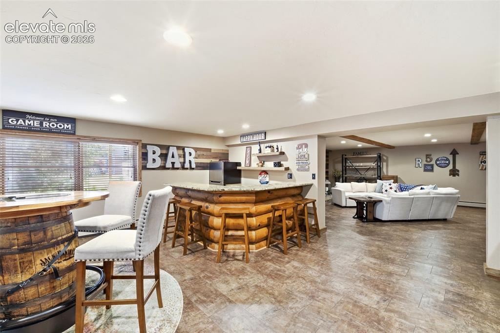 Image 27 of 49: Spacious entertainment area featuring a wood-clad bar with a stone countert