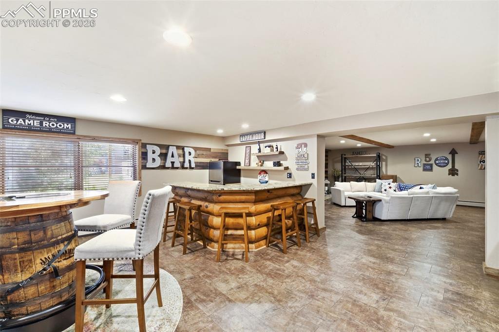 Image 29 of 50: Spacious entertainment area featuring a wood-clad bar with a stone countert