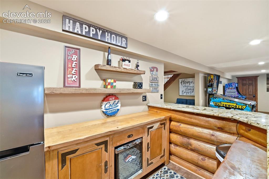 Image 29 of 49: Rustic bar area featuring a granite countertop, log-style bar front, wood-f